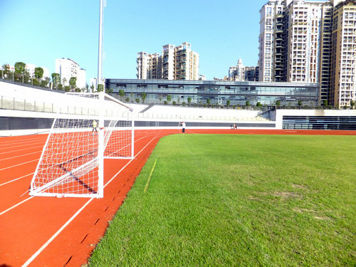 实拍深圳宝安体育馆足球场景观，有工人在维护有市民在跑步